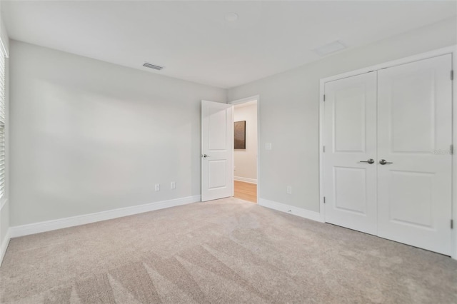 unfurnished bedroom featuring light colored carpet and a closet