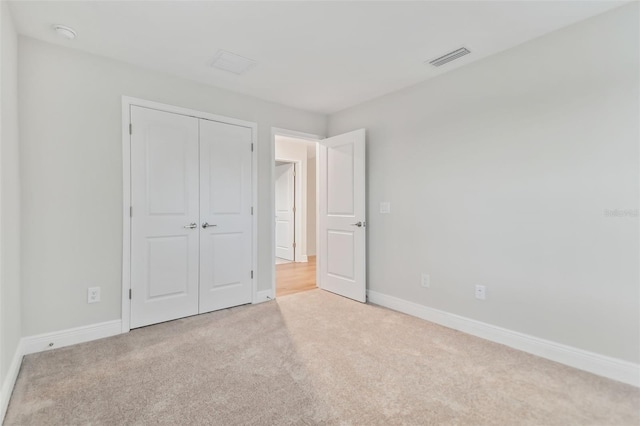 unfurnished bedroom with light colored carpet and a closet