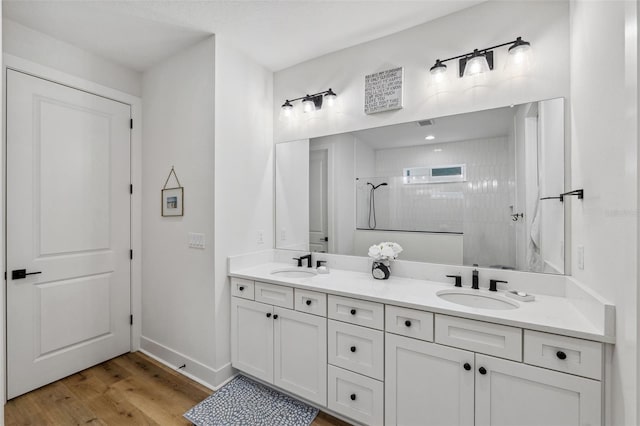 bathroom with hardwood / wood-style floors, vanity, and a tile shower