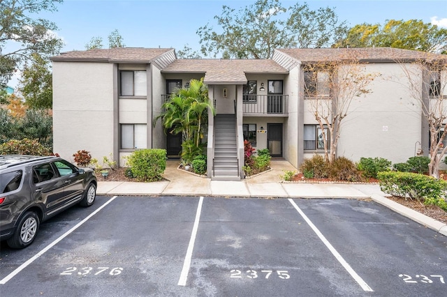 view of property with stairs and uncovered parking