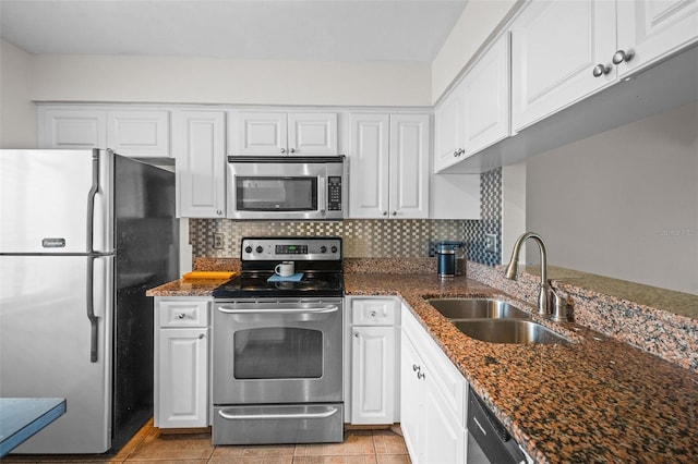 kitchen with appliances with stainless steel finishes, sink, white cabinetry, and dark stone counters