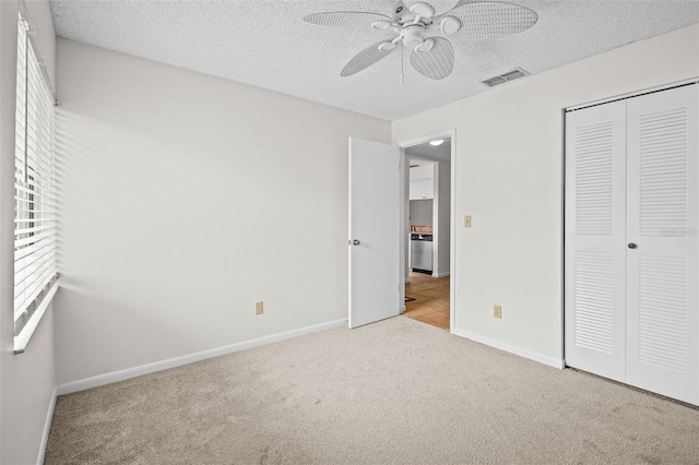 unfurnished bedroom featuring light carpet, ceiling fan, a closet, and a textured ceiling