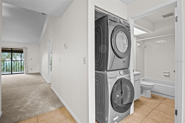 washroom featuring light colored carpet, stacked washer and clothes dryer, a textured ceiling, and ornamental molding