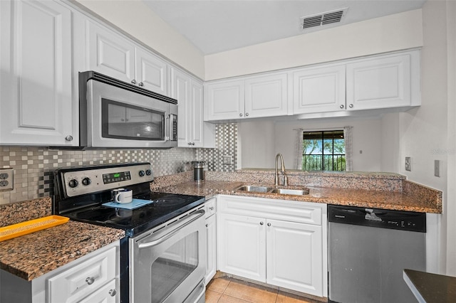 kitchen featuring visible vents, appliances with stainless steel finishes, white cabinetry, a sink, and dark stone counters