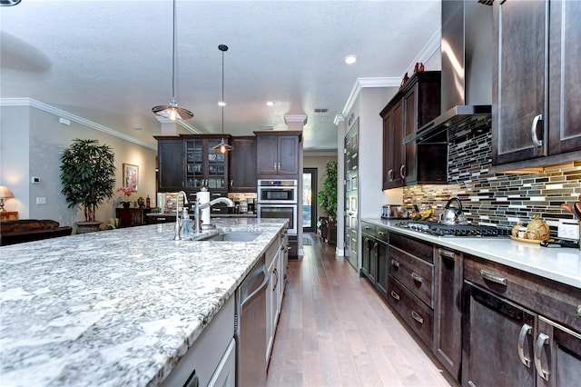 kitchen featuring wall chimney exhaust hood, crown molding, stainless steel appliances, and dark brown cabinets