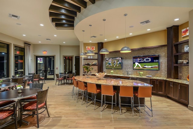 bar featuring pendant lighting, light hardwood / wood-style floors, light stone counters, and tasteful backsplash