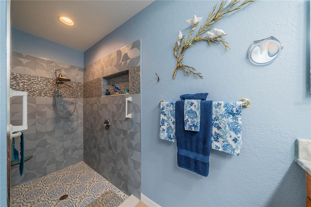 bathroom with tiled shower and tile patterned floors