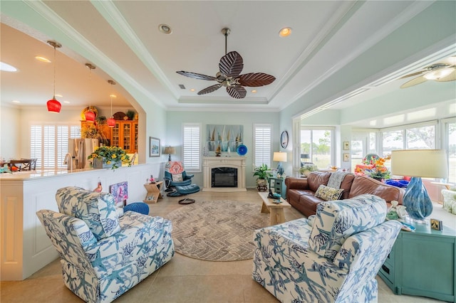 living room featuring crown molding, light tile patterned floors, ceiling fan, and a tray ceiling