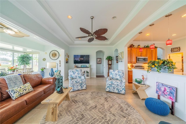 tiled living room with crown molding, ceiling fan, and a tray ceiling