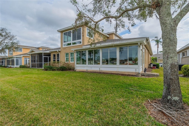 rear view of property featuring a sunroom and a lawn