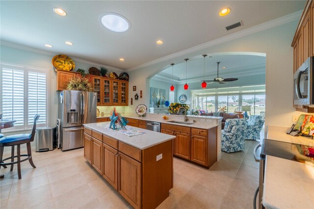 kitchen with pendant lighting, sink, stainless steel appliances, a kitchen island, and kitchen peninsula