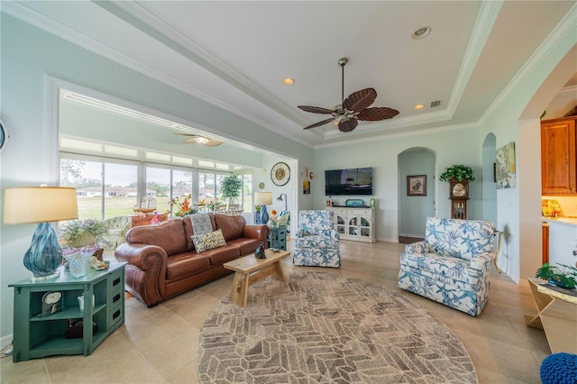 living room with crown molding, ceiling fan, a raised ceiling, and light tile patterned floors