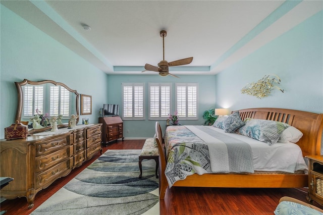 bedroom with ceiling fan, dark hardwood / wood-style floors, and a raised ceiling