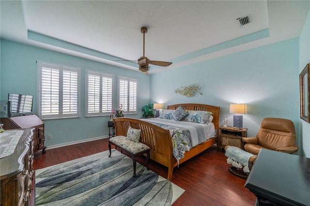 bedroom featuring a tray ceiling, dark hardwood / wood-style floors, and ceiling fan