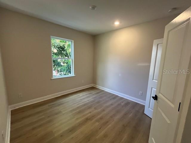 unfurnished room featuring dark wood-type flooring and baseboards