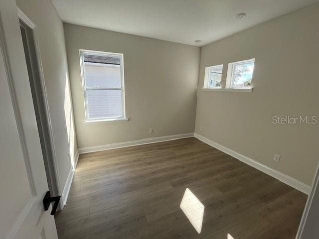 unfurnished room with dark wood-style floors and baseboards