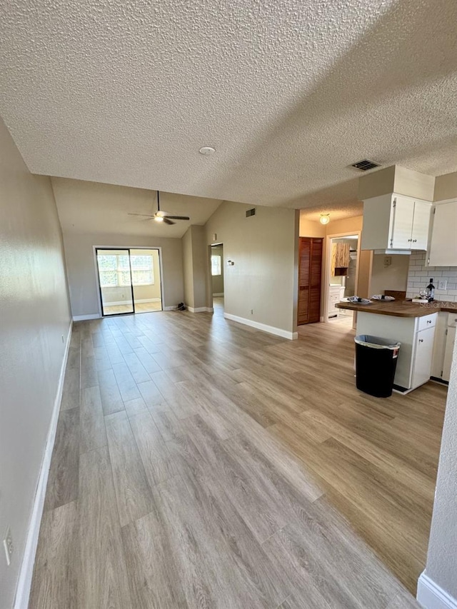 unfurnished living room featuring a textured ceiling, ceiling fan, and light hardwood / wood-style floors