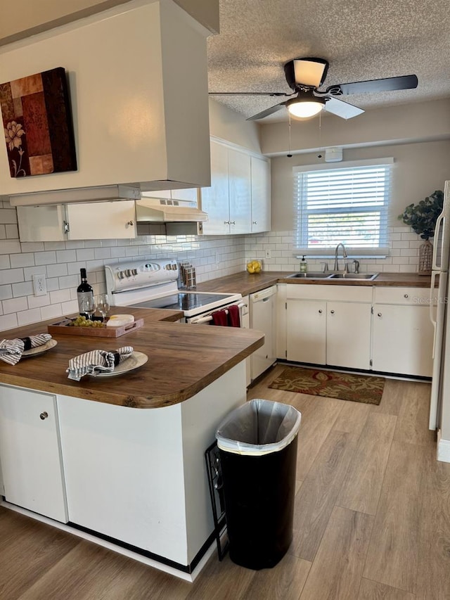 kitchen with kitchen peninsula, white appliances, a textured ceiling, white cabinets, and sink