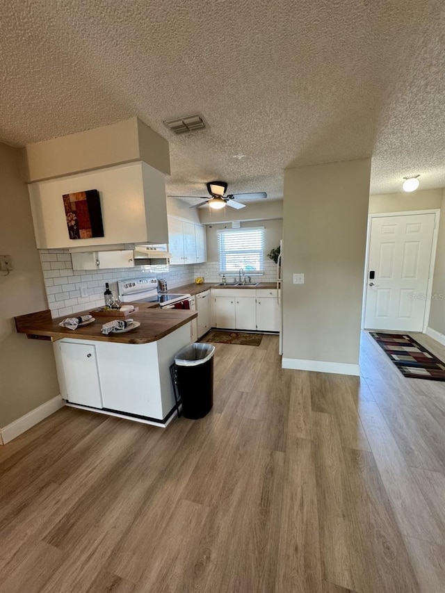 kitchen featuring white appliances, white cabinets, sink, backsplash, and kitchen peninsula