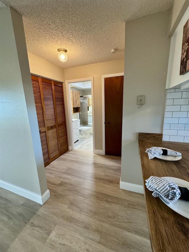 hallway featuring a textured ceiling and light hardwood / wood-style flooring