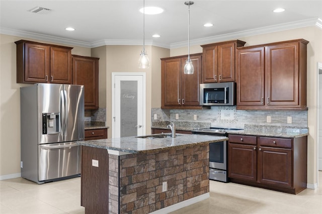 kitchen with decorative light fixtures, sink, a kitchen island with sink, stainless steel appliances, and light stone countertops