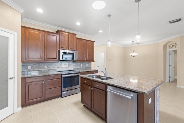 kitchen with pendant lighting, sink, appliances with stainless steel finishes, an island with sink, and decorative backsplash