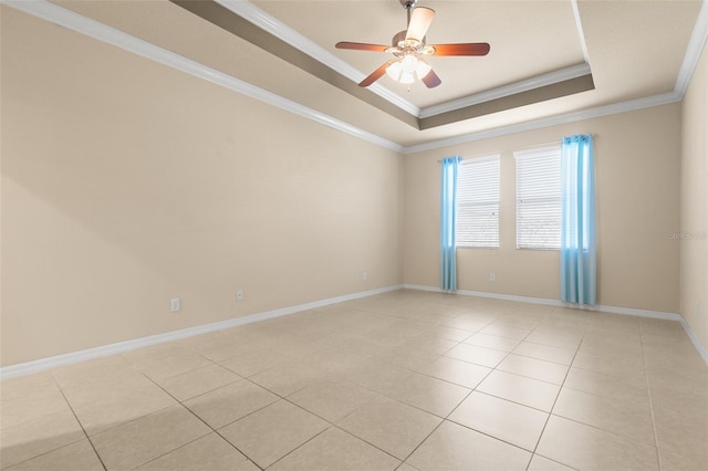 tiled empty room with a raised ceiling, ornamental molding, and ceiling fan