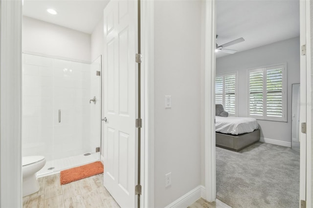 bathroom featuring ceiling fan, toilet, and a shower with door