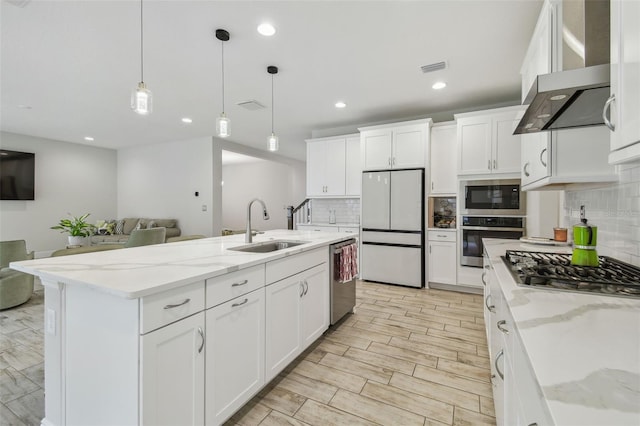 kitchen featuring decorative light fixtures, white cabinetry, a center island with sink, and appliances with stainless steel finishes