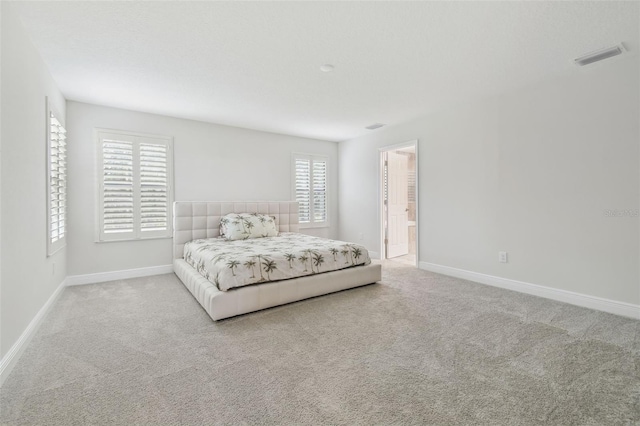 carpeted bedroom featuring multiple windows and ensuite bathroom