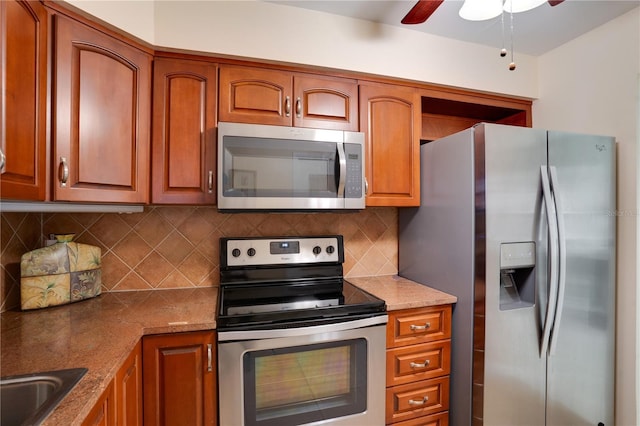 kitchen with sink, ceiling fan, stainless steel appliances, light stone counters, and decorative backsplash