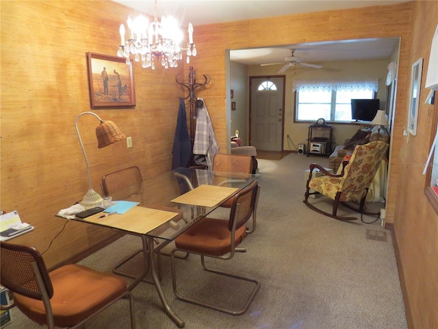 carpeted dining room with ceiling fan with notable chandelier