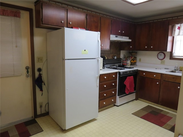 kitchen with sink, backsplash, range with gas cooktop, and white refrigerator