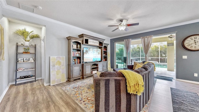 living room featuring a textured ceiling, ornamental molding, and light wood-type flooring