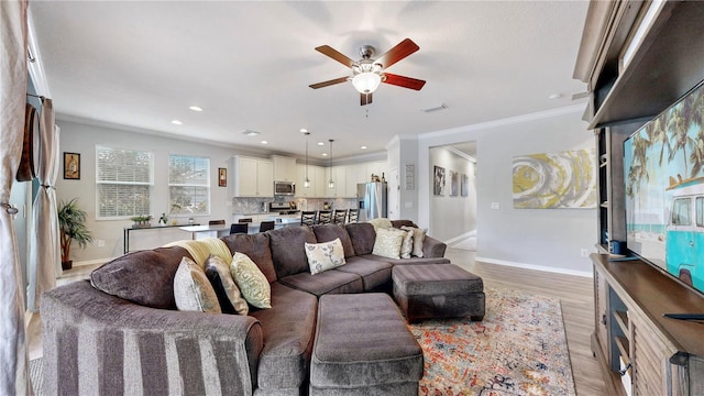 living room with ceiling fan, light wood-type flooring, and crown molding