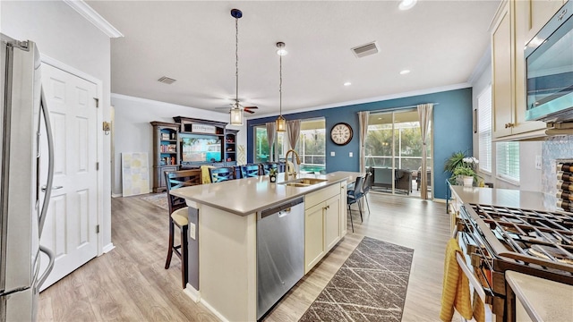 kitchen with stainless steel appliances, an island with sink, light hardwood / wood-style floors, hanging light fixtures, and ceiling fan