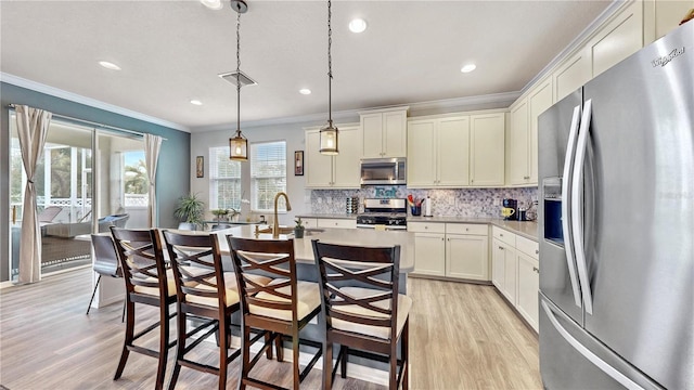 kitchen with appliances with stainless steel finishes, decorative backsplash, decorative light fixtures, light wood-type flooring, and sink