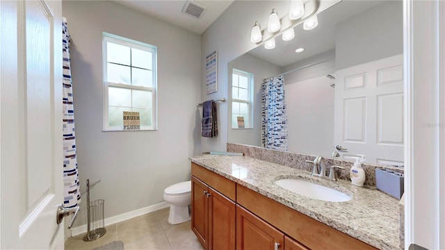 bathroom with toilet, vanity, tile patterned flooring, and a wealth of natural light