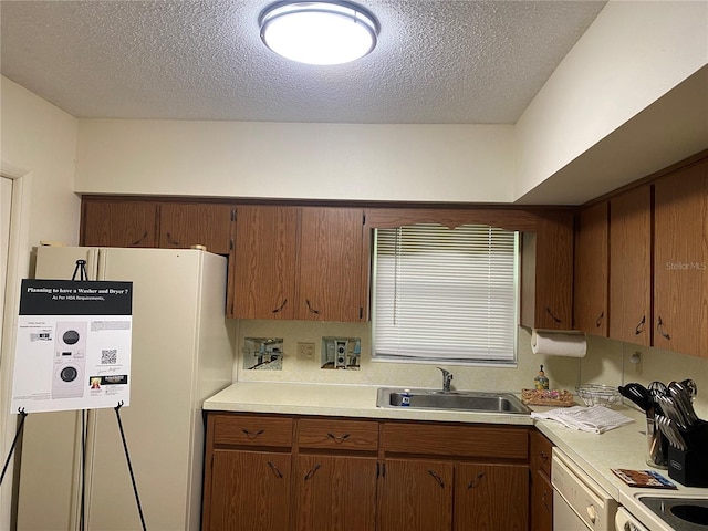 kitchen featuring fridge, dishwasher, sink, and a textured ceiling