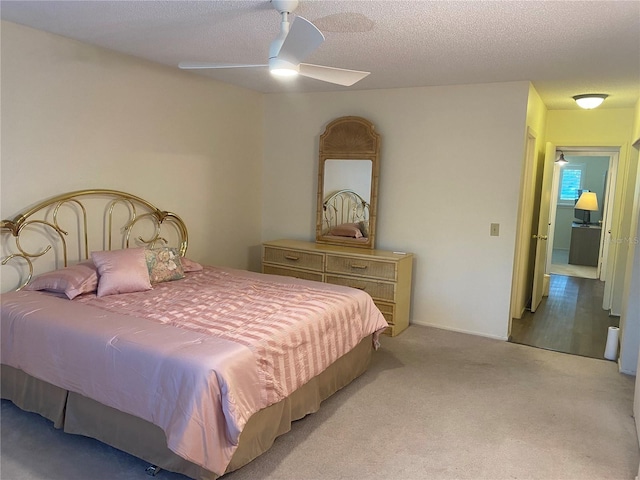 carpeted bedroom featuring ceiling fan and a textured ceiling