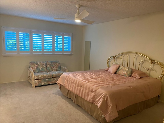 bedroom with ceiling fan, light colored carpet, and a textured ceiling