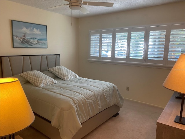 bedroom with ceiling fan, multiple windows, a textured ceiling, and carpet flooring