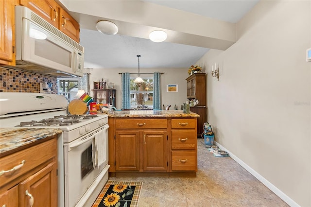 kitchen featuring kitchen peninsula, a wealth of natural light, white appliances, and pendant lighting