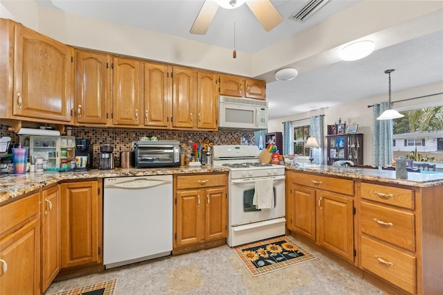 kitchen featuring a healthy amount of sunlight, kitchen peninsula, pendant lighting, and white appliances