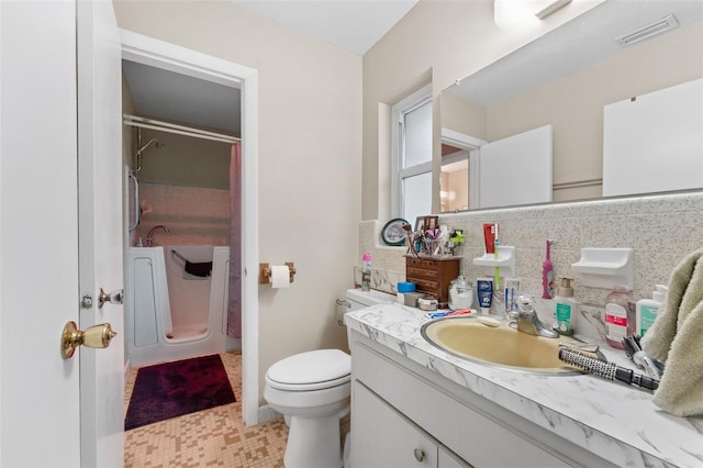 bathroom featuring toilet, decorative backsplash, and vanity