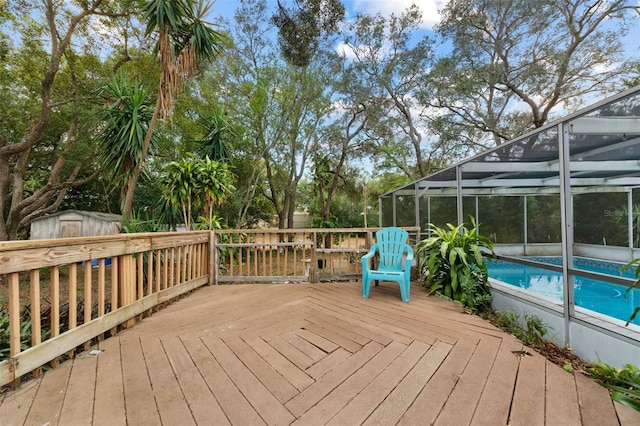 wooden terrace featuring glass enclosure and a shed