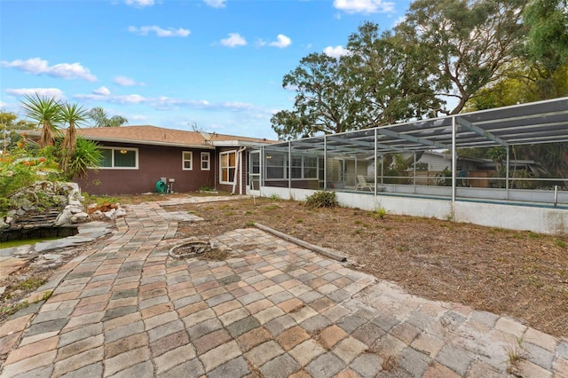 rear view of property featuring glass enclosure and a patio area