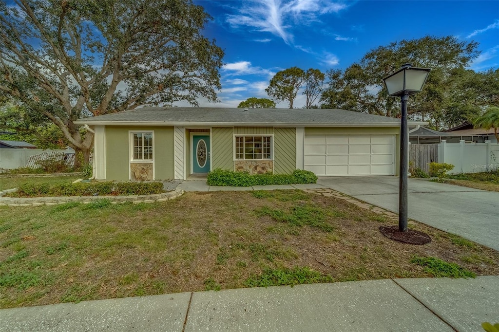 single story home featuring a garage, a front yard, concrete driveway, and fence