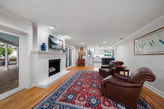 living room featuring a brick fireplace, crown molding, and light hardwood / wood-style flooring