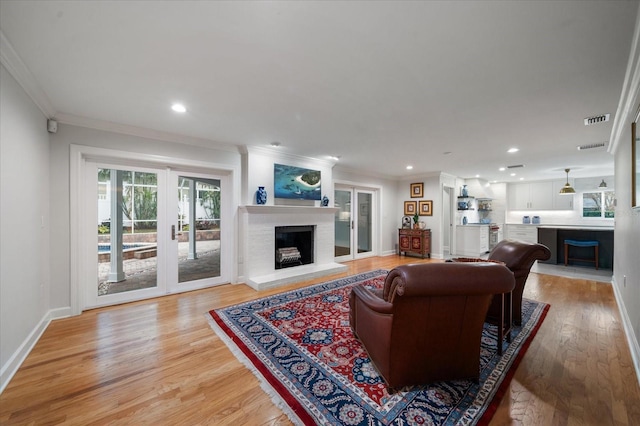 living room featuring a brick fireplace, hardwood / wood-style flooring, and crown molding